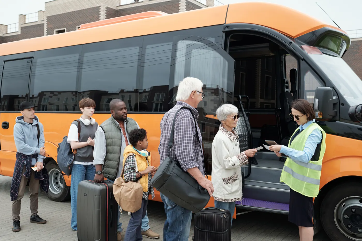 Passengers boarding a scheduled bus while the operator checks tickets